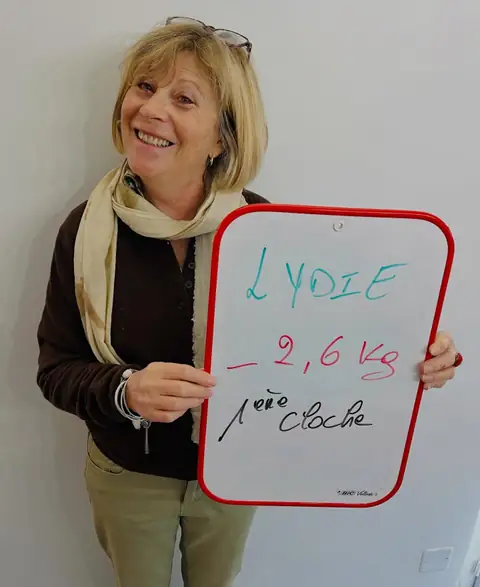 Une ardoise blanche, un bilan écrit dessus, une membre qui le présente depuis la salle du club